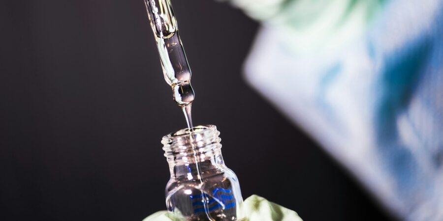 A medical professional adding liquid to a small vial.