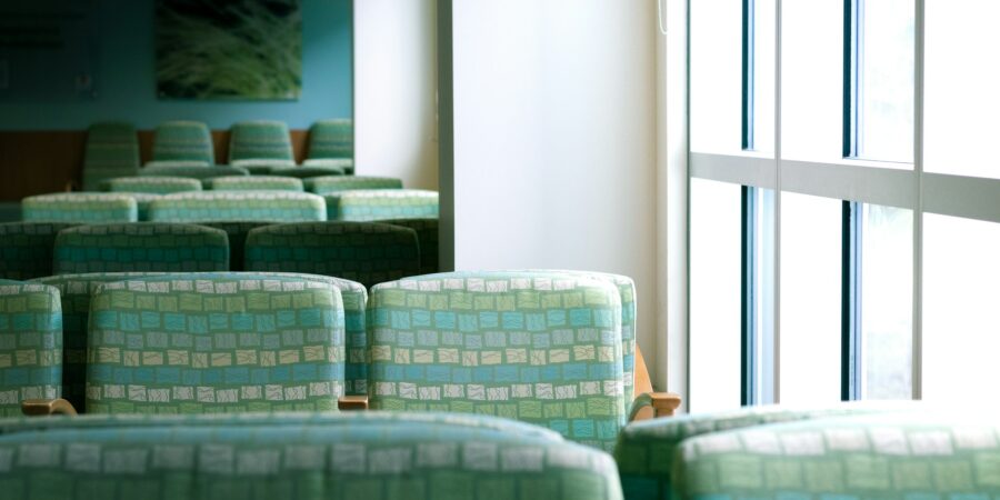 Waiting area with green upholstered chairs and a large window.