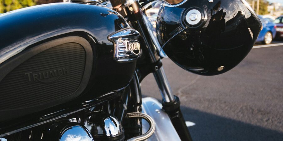 A parked motorcycle with a helmet hanging on one of the handlebars.