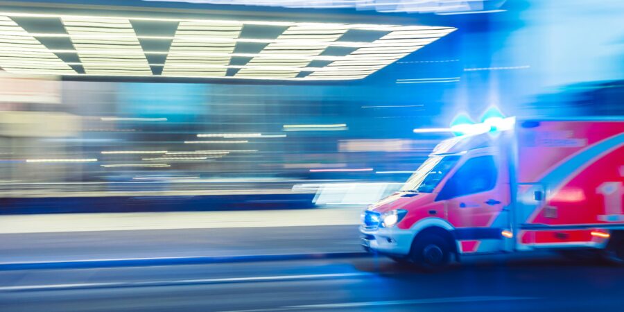 A blurred image of an ambulance driving with lights on, indicating a speedy response to an emergency.