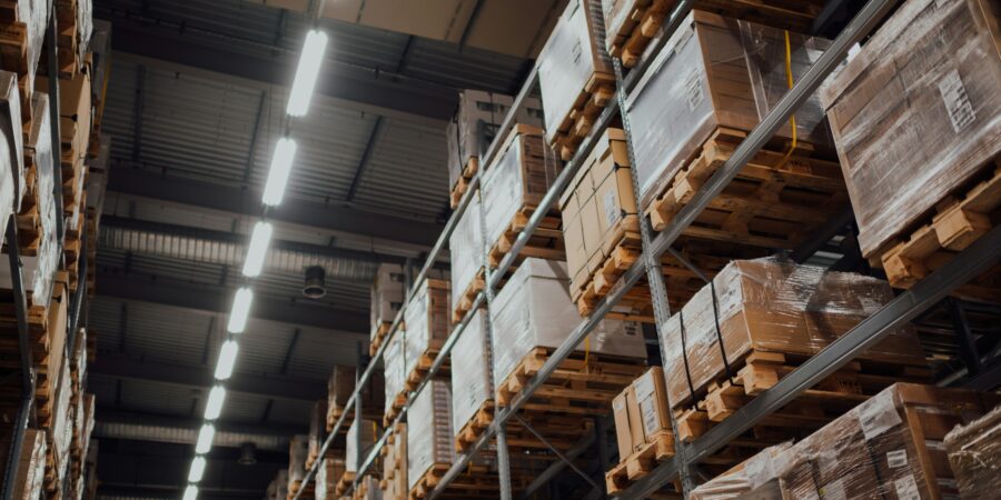 A warehouse interior with high shelves stacked with cardboard boxes on pallets.