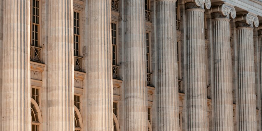 A close-up of a government or institutional building with classical architecture facade with rows of tall, stone columns.