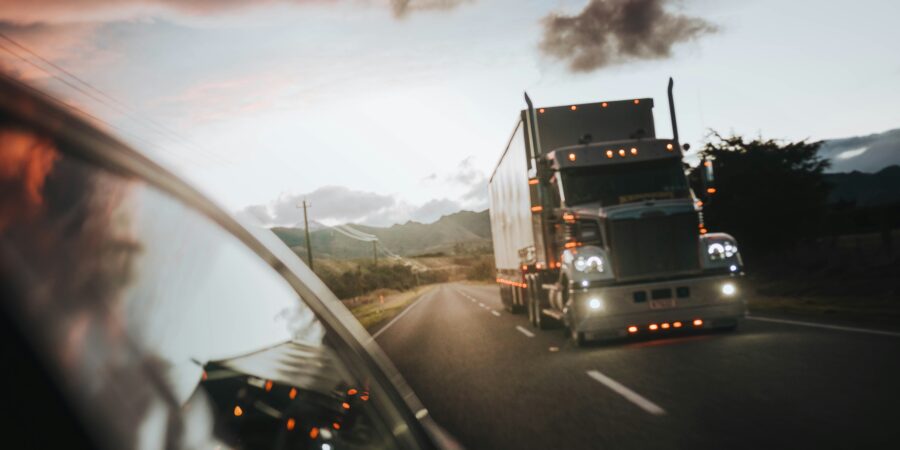 A white semi-trailer truck driving on a highway at sunset.