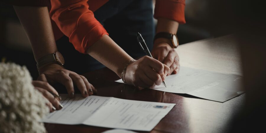 A close up of two people reviewing and signing legal documents on a table.